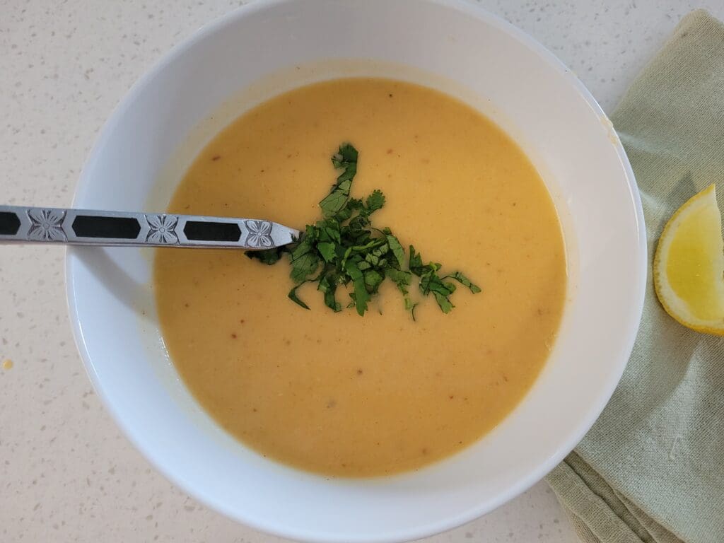 Bowl of creamy butternut squash soup garnished with herbs.