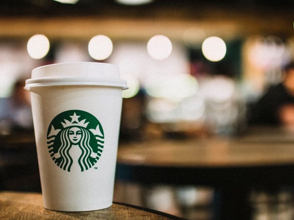 A Starbucks cup on a table with a blurred-out cafe in the background